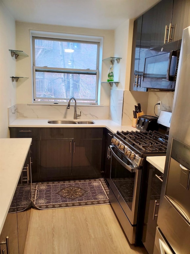 kitchen with stainless steel appliances, a wealth of natural light, a sink, and wood finished floors