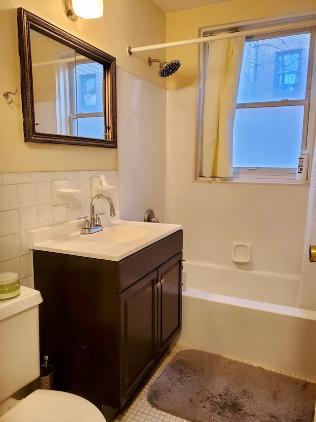 bathroom featuring tile patterned flooring, toilet, vanity, tile walls, and tub / shower combination