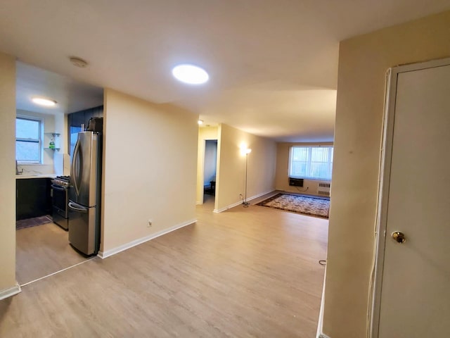 empty room featuring radiator, light wood finished floors, and baseboards