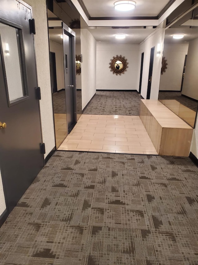 corridor featuring ornamental molding, a tray ceiling, and tile patterned floors