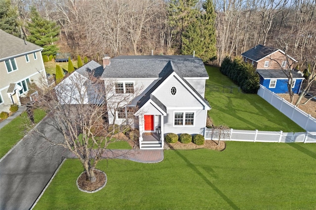 view of front facade featuring aphalt driveway, fence, a chimney, and a front lawn