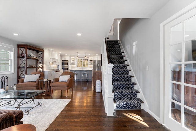 living area featuring dark wood-style floors, stairway, baseboards, and recessed lighting