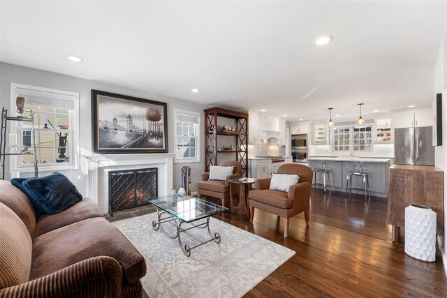 living area featuring a fireplace with flush hearth, recessed lighting, and dark wood-style flooring