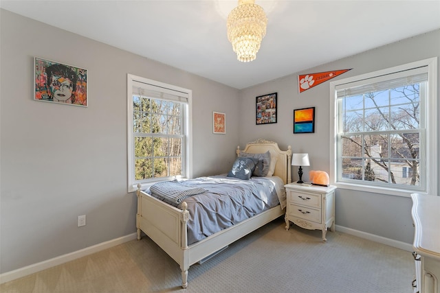 bedroom featuring light carpet, baseboards, and a chandelier