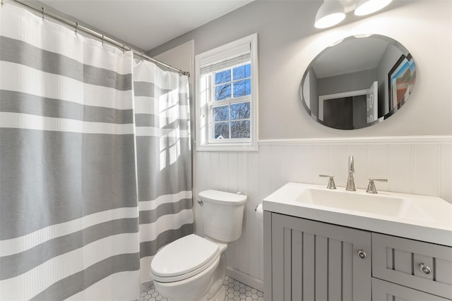 full bath with toilet, a wainscoted wall, and vanity