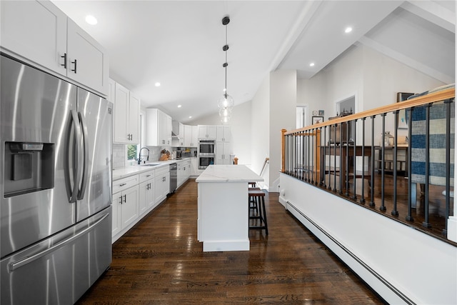 kitchen with dark wood finished floors, lofted ceiling, stainless steel appliances, a baseboard heating unit, and a sink