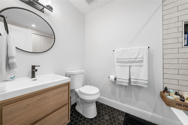 bathroom with toilet, visible vents, baseboards, vanity, and tile patterned floors