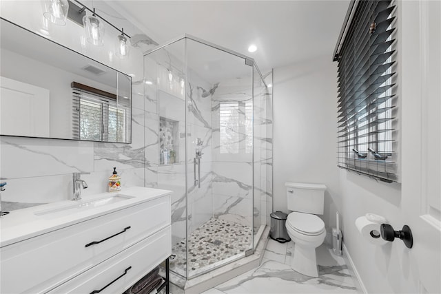 bathroom featuring marble finish floor, a marble finish shower, toilet, vanity, and baseboards