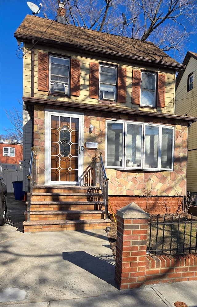 view of front facade with entry steps, cooling unit, fence, and a chimney