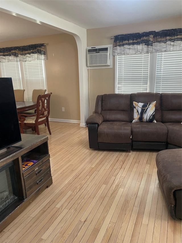 113-21 203rd St, Saint Albans, NY 11412 - living room with a wall mounted air conditioner, light wood-style flooring, arched walkways, and baseboards