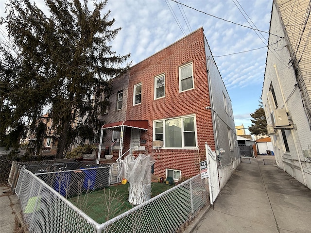 view of front facade with brick siding, ac unit, and fence private yard