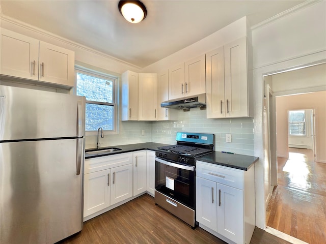 kitchen featuring dark countertops, under cabinet range hood, appliances with stainless steel finishes, and a sink