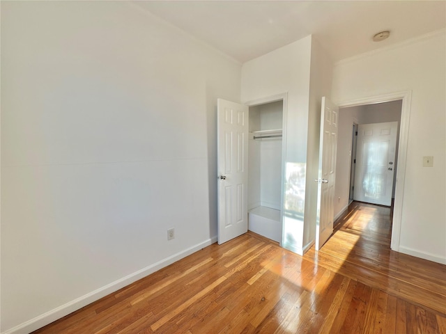 unfurnished bedroom featuring a closet, light wood-style flooring, and baseboards