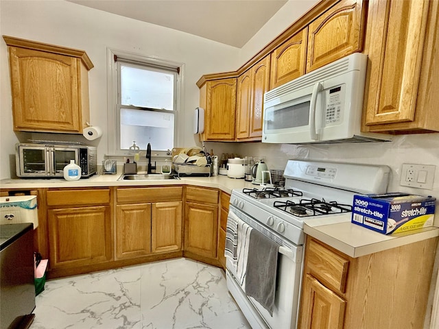 kitchen featuring white appliances, a sink, marble finish floor, light countertops, and brown cabinetry