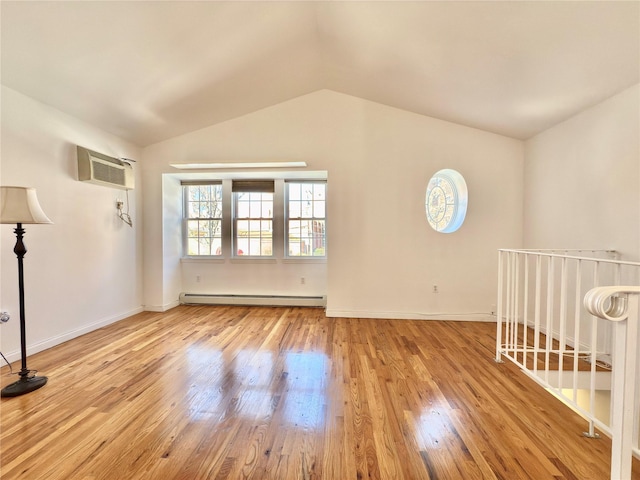 empty room featuring baseboards, lofted ceiling, wood finished floors, a baseboard heating unit, and a wall mounted AC