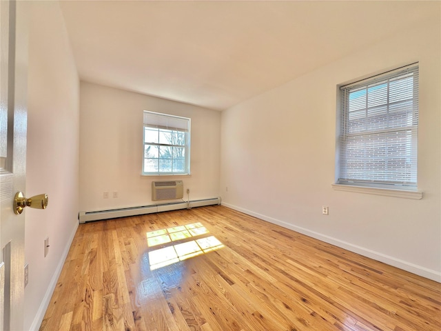 spare room with a baseboard radiator, a wall mounted AC, baseboards, and wood finished floors