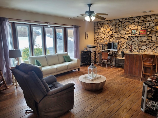 living room featuring hardwood / wood-style flooring, ceiling fan, and visible vents