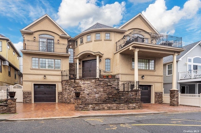 view of front of property featuring a garage, stone siding, driveway, and stucco siding