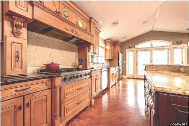 kitchen with stainless steel appliances, dark wood-style flooring, visible vents, vaulted ceiling, and tasteful backsplash