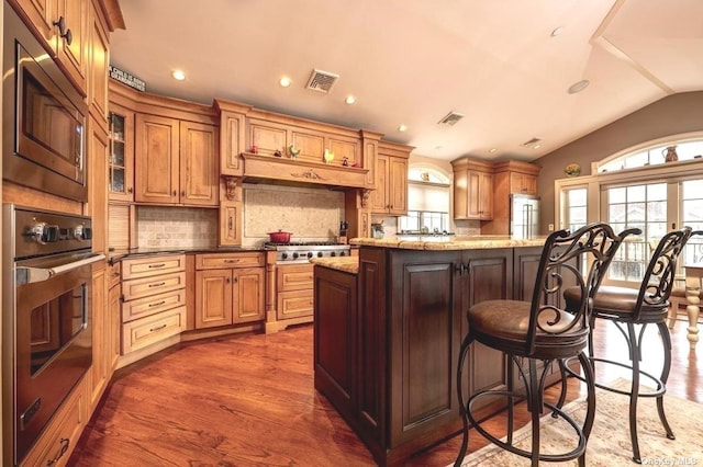 kitchen with stainless steel appliances, lofted ceiling, visible vents, and a breakfast bar