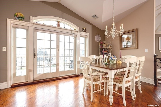 dining space with lofted ceiling, a chandelier, wood finished floors, visible vents, and baseboards