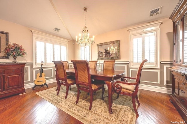 dining space featuring lofted ceiling, dark wood-style floors, visible vents, and a decorative wall