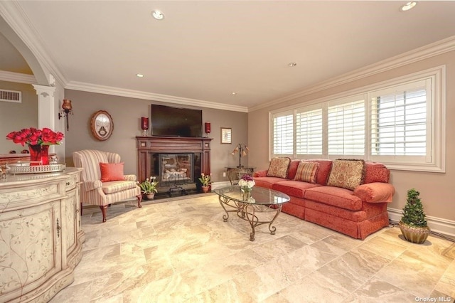 living room featuring a fireplace with raised hearth, visible vents, crown molding, and ornate columns