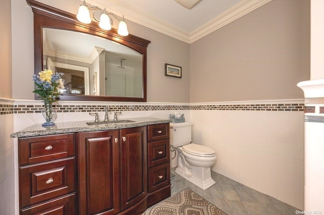 bathroom with toilet, a wainscoted wall, ornamental molding, vanity, and tile walls