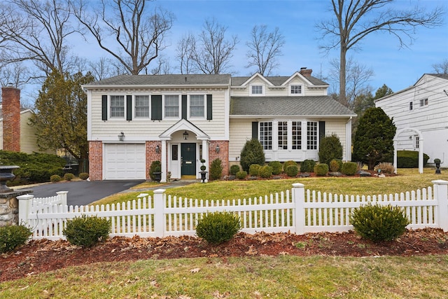 view of front of home featuring aphalt driveway, brick siding, and a fenced front yard