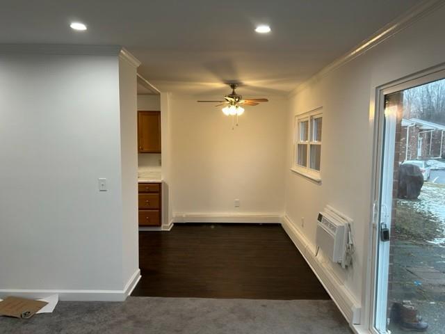 empty room with recessed lighting, dark carpet, baseboards, and a wall mounted AC