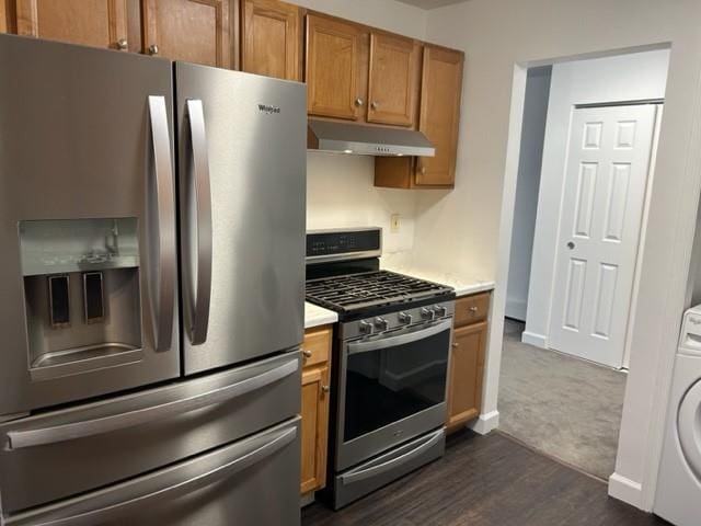 kitchen with brown cabinets, washer / clothes dryer, light countertops, appliances with stainless steel finishes, and under cabinet range hood