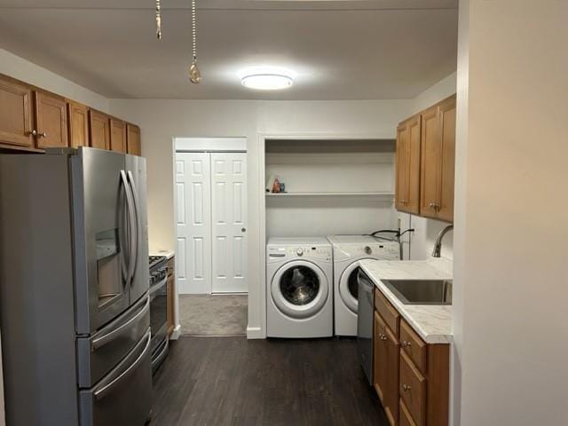 clothes washing area featuring dark wood-style floors, laundry area, separate washer and dryer, and a sink