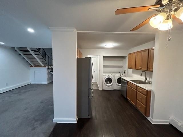 kitchen with a sink, light countertops, appliances with stainless steel finishes, independent washer and dryer, and brown cabinetry