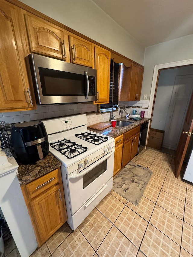 kitchen featuring black dishwasher, white gas range oven, stainless steel microwave, a sink, and backsplash