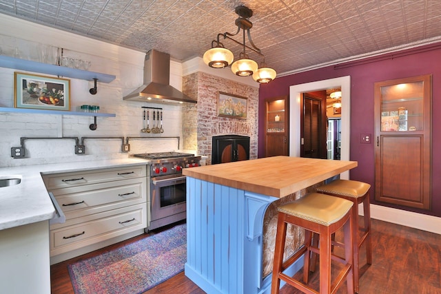 kitchen featuring wall chimney exhaust hood, an ornate ceiling, wood counters, high end range, and open shelves