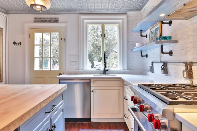 kitchen featuring an ornate ceiling, butcher block countertops, appliances with stainless steel finishes, open shelves, and a sink