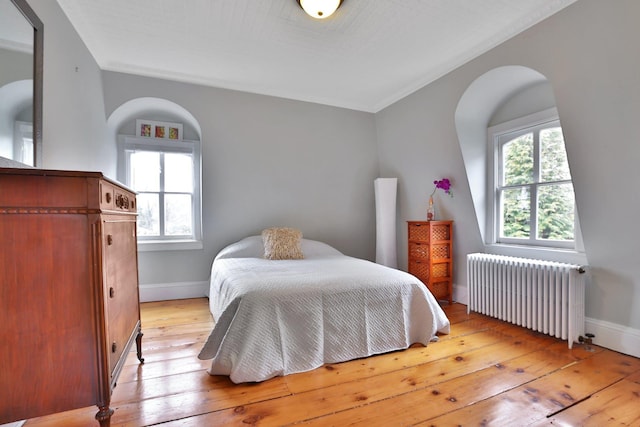 bedroom featuring radiator, light wood-style flooring, and baseboards