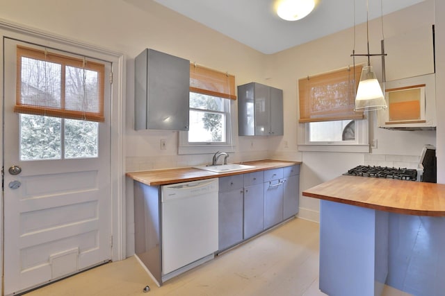 kitchen featuring dishwasher, butcher block countertops, stove, gray cabinetry, and a sink