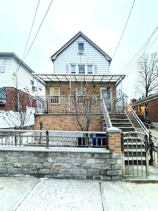 view of front of house with covered porch, a fenced front yard, stairs, and brick siding