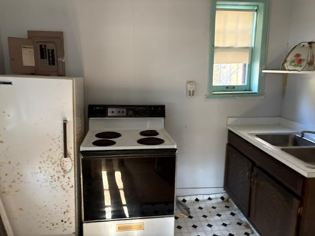 kitchen featuring a sink, baseboards, electric stove, light countertops, and freestanding refrigerator