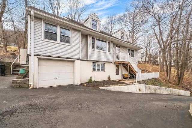 view of front of home featuring a garage, driveway, stucco siding, and stairway