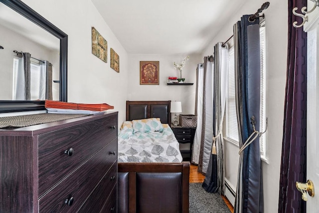bedroom with multiple windows and a baseboard heating unit