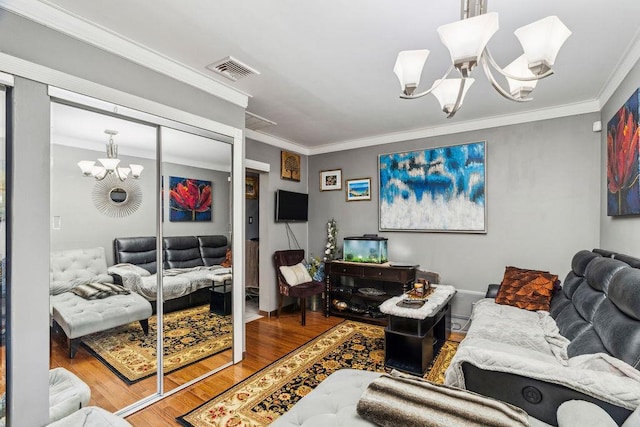 living area featuring a chandelier, visible vents, ornamental molding, and wood finished floors