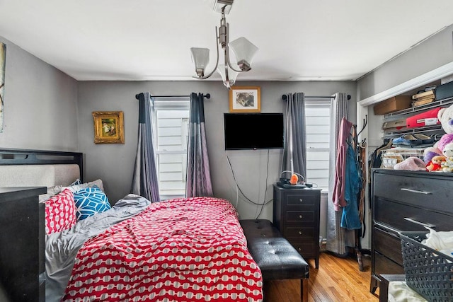 bedroom with wood finished floors and an inviting chandelier