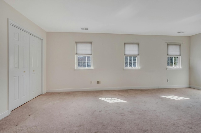 interior space with a closet, carpet flooring, visible vents, and baseboards