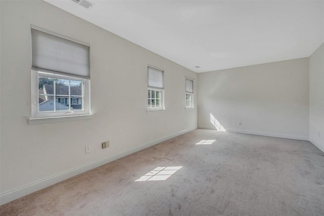 unfurnished room with carpet floors, visible vents, and baseboards