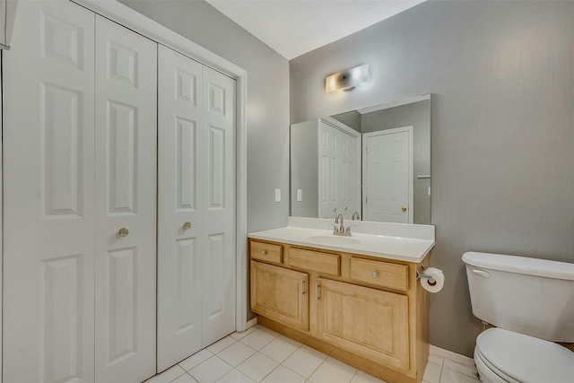 bathroom with a closet, vanity, toilet, and tile patterned floors