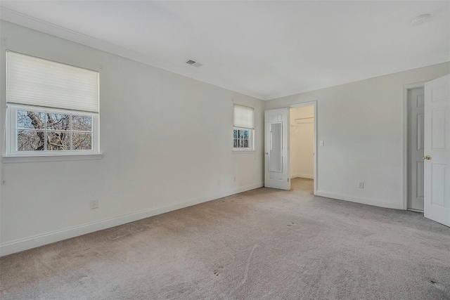 unfurnished bedroom featuring carpet floors, crown molding, a spacious closet, and baseboards