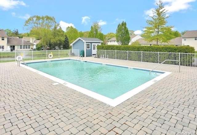 pool featuring an outbuilding, a patio area, and fence