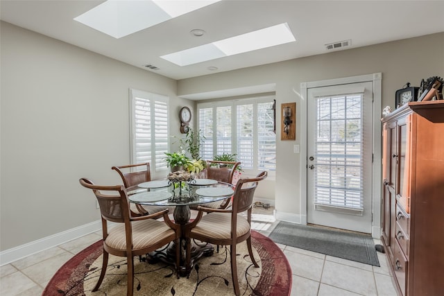 dining room featuring light tile patterned floors, a skylight, visible vents, and baseboards